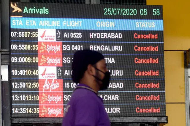 An airport staff walks past a display board that shows all arrival flights cancelled