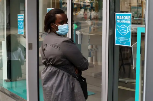 A woman wearing a mask goes into a shop in Antwerp