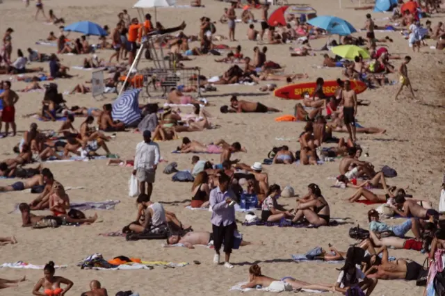 Beachgoers bask in the sun as they enjoy a warm afternoon at La Nova Icaria beach in Barcelona on 17 July