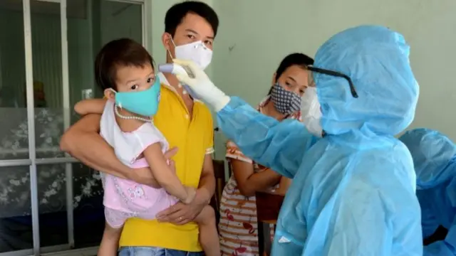 A health worker checks the temperature of residents at the area of a newly found coronavirus infected patient in Danang, Vietnam July 26, 2020