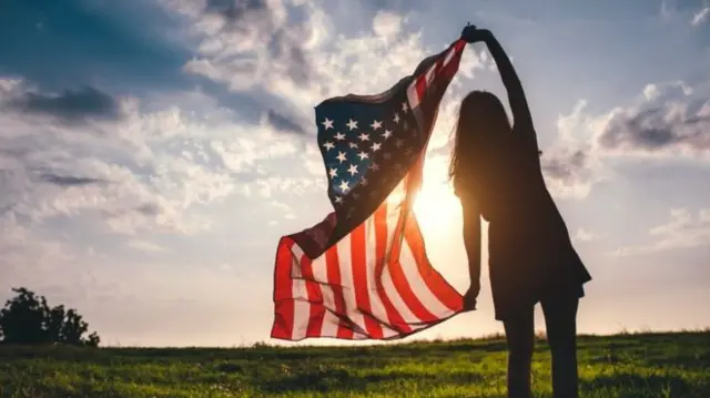 A woman holds up the US flag