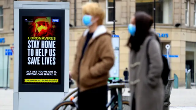 Two people in front of a coronavirus sign