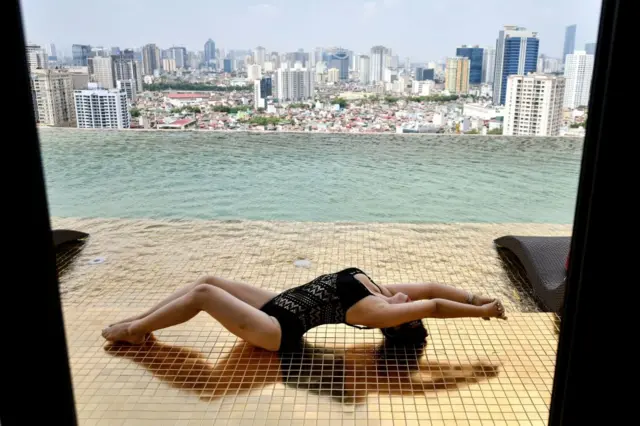 Guest poses in a gold-plated infinity pool at The Dolce Hanoi Garden Lake