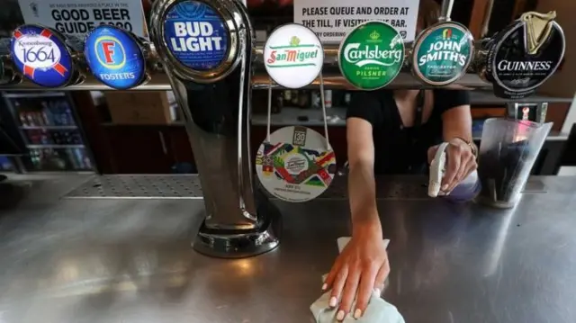 A woman cleaning a bar at a pub