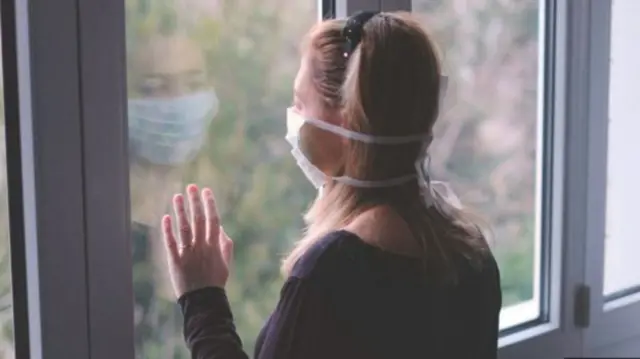 Person, masked, looking out of window