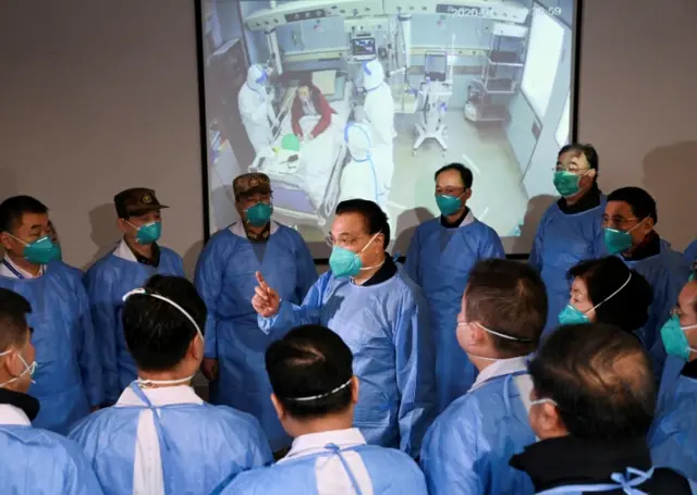 Chinese Premier Li Keqiang wearing a mask and protective suit speaks to medical workers