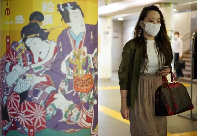 A young woman wearing a protective mask walks through the underground in Roppongi district in Tokyo