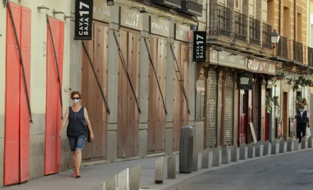 A woman wearing a mask walks through the streets of Madrid