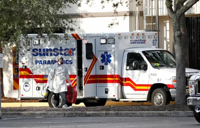 A paramedic dressed in protective equipment outside an ambulance