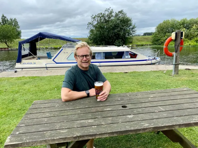 Man enjoying a pint on the river bank