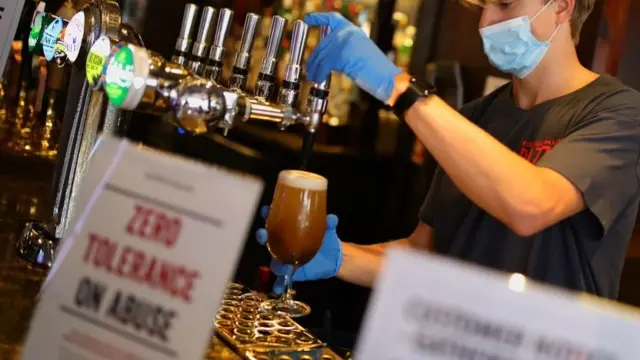 Bar staff in PPE pour drinks at the reopening The Toll Gate, a Wetherspoons pub in Hornsey, north London, as coronavirus lockdown restrictions are eased across England