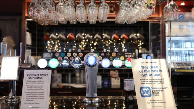 Customer information signs at the bar of the Shakespeare"s Head pub in Holborn, London, as it reopens for business as coronavirus lockdown restrictions are eased across England.