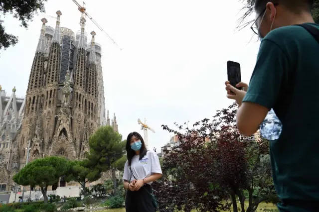 A tourist poses for a picture in front of the Sagrada Familia basilica in Barcelona. Photo: June 2020