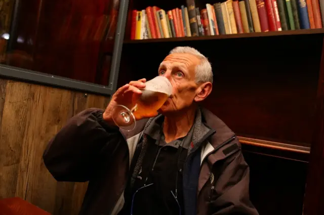 Michael Robinson drinks a pint