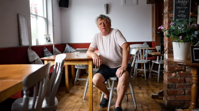 John Turner, landlord of The Dolphin pub in Llanymynech, where the border for England and Wales runs along the A483. Drinking establishments on one side of the A road such as The Cross Keys and The Bradford Arms will welcome customers on Saturday 4th July,