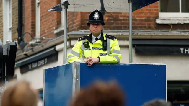 A police officer stands at an elevated position to watch people drinking after the reopening of commercial activities, following the outbreak of the coronavirus disease