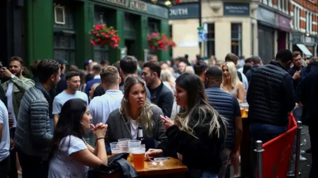 People sit and drink at the Borough Market after the reopening of commercial activities following the outbreak of the coronavirus disease