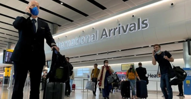 A pilot is seen wearing a protective face mask at Heathrow Airport