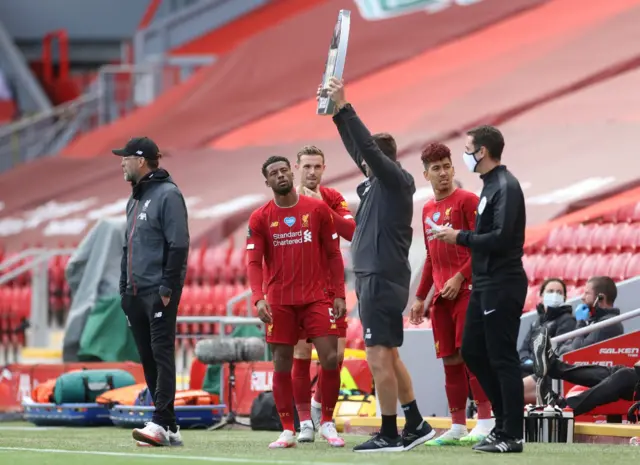 Liverpool"s Georginio Wijnaldum, Jordan Henderson and Roberto Firmino wait to come on as substitutes as manager Juergen Klopp looks on