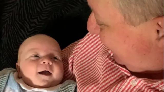 Douglas Fry holds his six-week-old grandson Hudson for the first time