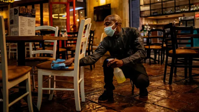 A waiter sanitises a chair in a restaurant at the Montecasino complex in Johannesburg