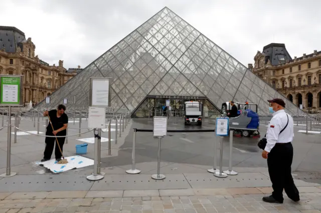 Workers clean the Louvre entrance the day before the official reopening