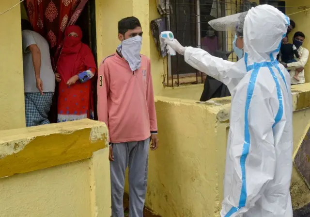 Health worker checks temperature of a Mumbai resident in India