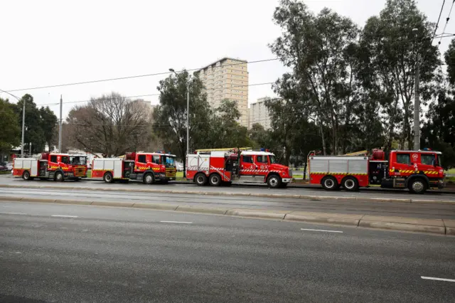 Firetrucks are seen lined up along Mt Alexander Road, behind the block of public housing towers in Kensington, Melbourne