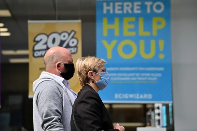 Shoppers wearing face coverings as a precautionary measure against spreading COVID-19, walk in the city centre of Leicester, central England, on June 30, 2020.