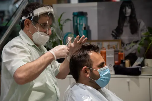 A man gets a haircut wearing mask and gloves in Tel Aviv