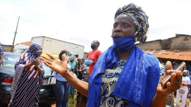 Nigerian woman wearing face covering and talking to camera