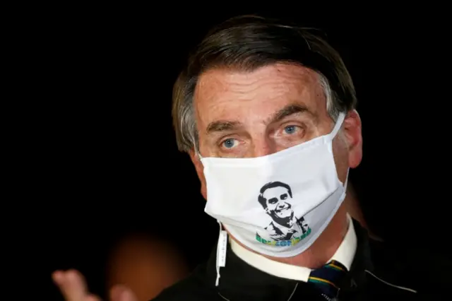President Jair Bolsonaro speaks with journalists while wearing a protective face mask as he arrives at Alvorada Palace, amid the coronavirus disease (COVID-19) outbreak, in Brasilia, Brazil, May 22, 2020.