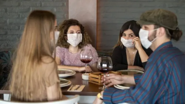 People eating a meal out while wearing face masks