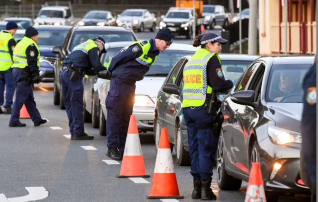 Police checking a queue of cars crossing the border into New South Wales