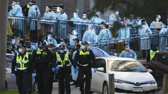 Police and healthcare workers outside a locked-down tower block in Melbourne