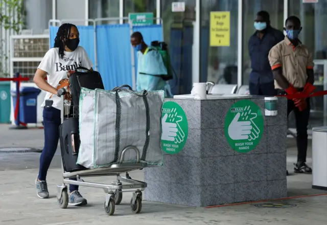 A passenger wearing a face mask pushes a trolley outside the Nnamdi Azikiwe International Airport