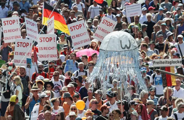 Demonstrators hold banners reading "Stop! It is enough! Enough is enough" during a demo in Berlin