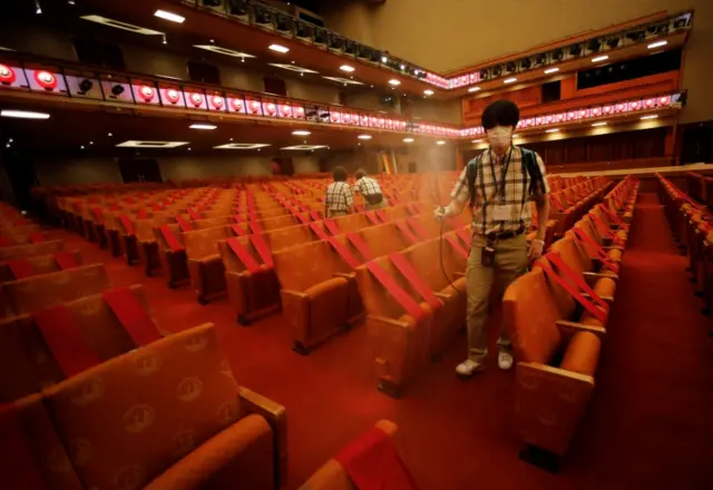 Workers wearing protective face masks disinfect seats at the Kabukiza Theatre