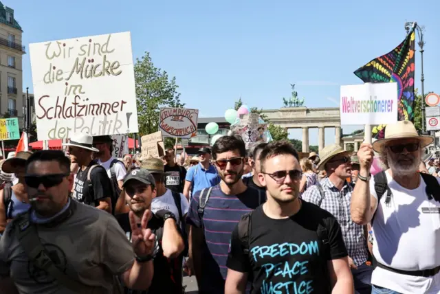 Demonstrators hold banners during a protest against the government's restrictions amid the coronavirus disease