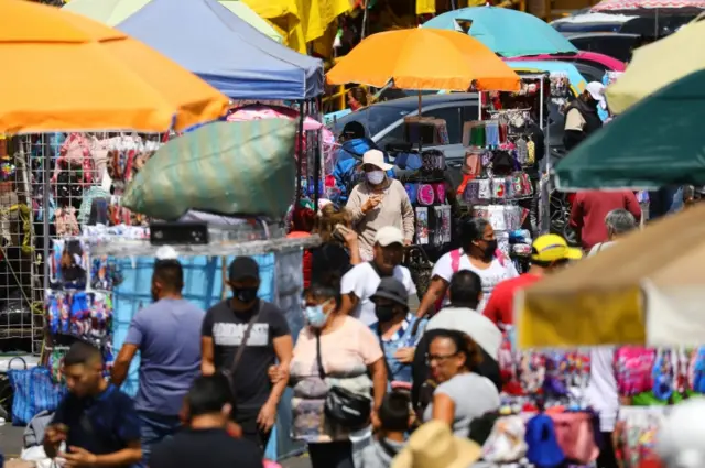 A woman wearing a face mask walks among other people at Sonora market in Mexico City