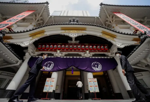 Staff members wearing protective face masks conduct a simulation on how to support social distancing at the entrance of the Kabukiza Theatre