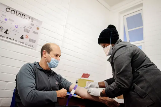 A medical worker injects a patient with a trial vaccine