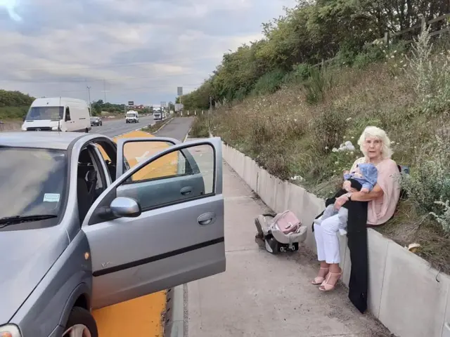 Melissa's elderly mum sits on the slope on the side of the M5.