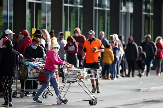 People queue outside a supermarket in Henderson in Auckland