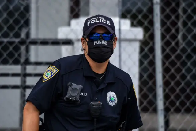 Police officer in Miami wearing a cap, sunglasses and a black face mask