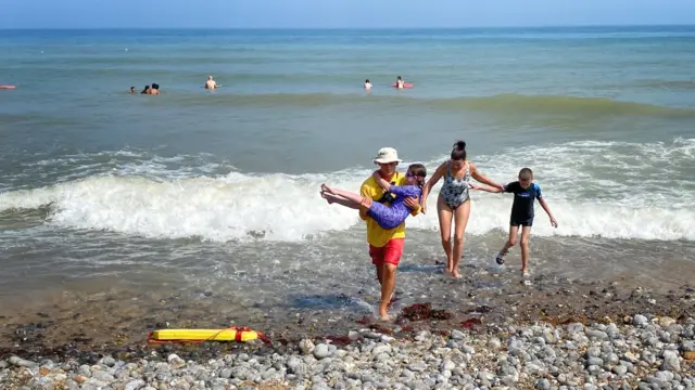 Girl being carried out of the sea by a lifeguard at Cromer