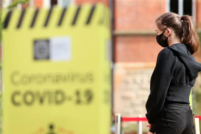 A student dressed in black with a black face covering on