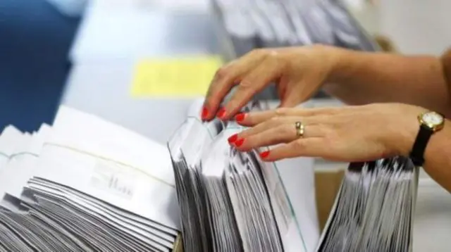 A woman rifles through exam result envelopes