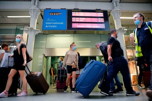 Passengers wearing facemasks as a precaution against the spread of the novel coronavirus walk through arrivals onto the main concourse at St Pancras International station in London on August 14, 2020