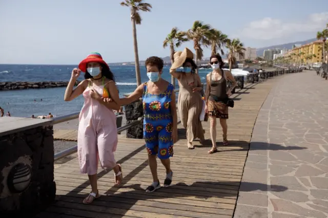 Tourists wearing masks walk by the seaside in the town of Candelaria, Tenerife, Canary Islands, Spain